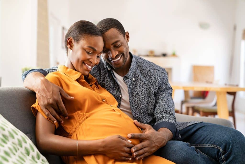 Pregnant woman and husband looking lovingly at unborn child.