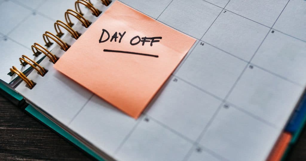 Shot of a notebook and a sticky note saying “day off” stuck to it on a desk